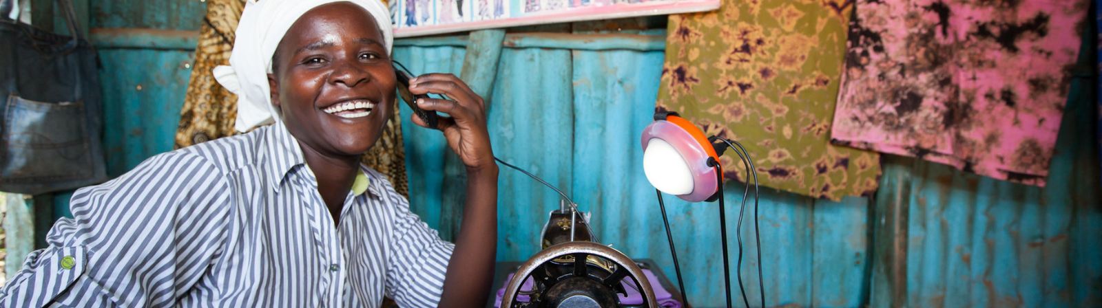 Rose Owino a tailor in Migori, uses a solar light to charge her phone during the day, Migori, Kenya