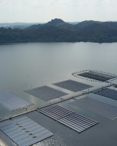 Aerial view of a large utility-scale floating solar photovoltaic (PV) system installed on a calm body of water