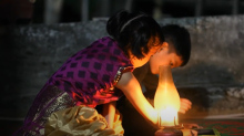 woman and child doing homework at night next to candle